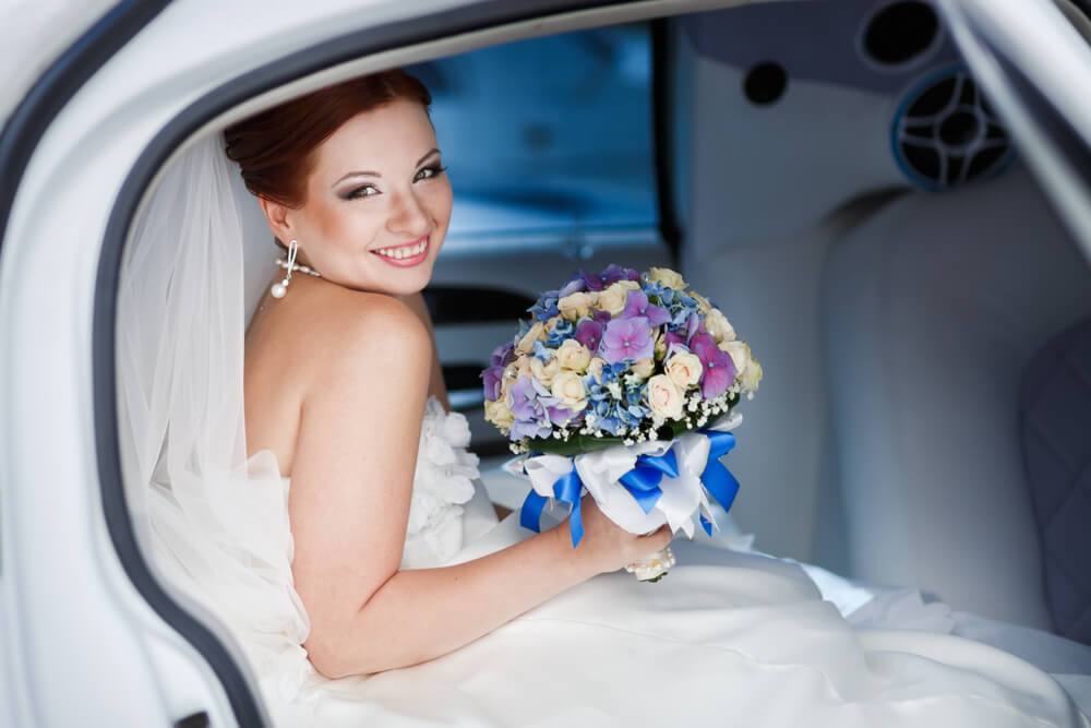 Bride in white wedding limo with colorful bouquet in Phoenix